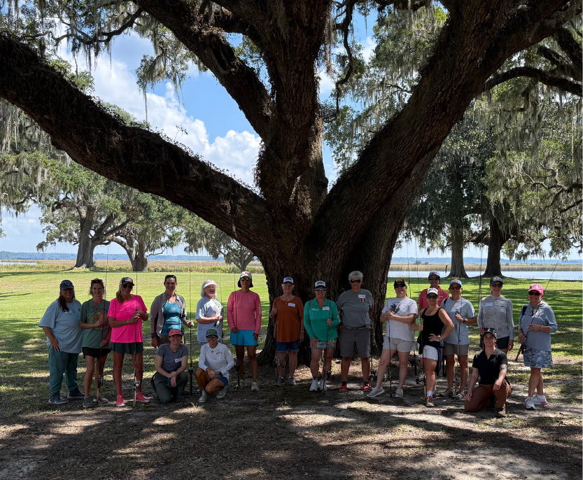 group of anglers in front of ancient tree and water